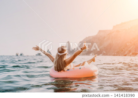 Woman, sea, vacation. Happy woman floating on inflatable ring at sea with arms outstretched, sunny cliff background. Woman, sea, vacation. Happy woman floating on inflatable ring at sea with arms outstretched, sunny cliff background. 141418390