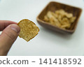 A hand picking up a single potato chip A hand picking up a single potato chip 141418592