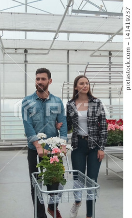 Vertical video Young couple Buying Flowers in a Sunlit Garden Shop. 4K. Coupe shopping for decorative plants on a sunny floristic greenhouse market. Home and Garden concept. Vertical video Young couple Buying Flowers in a Sunlit Garden Shop. 4K. Coupe shopping for decorative plants on a sunny floristic greenhouse market. Home and Garden concept. 141419237