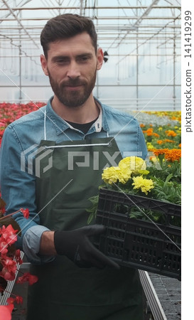 Vertical video Worker walking in a flowerpot. Agricultural engineer working in greenhouse. Vertical video Worker walking in a flowerpot. Agricultural engineer working in greenhouse. 141419299