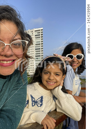 Mother and daughters posing at coastal boardwalk. UGC Mother and daughters posing at coastal boardwalk. UGC 141419994