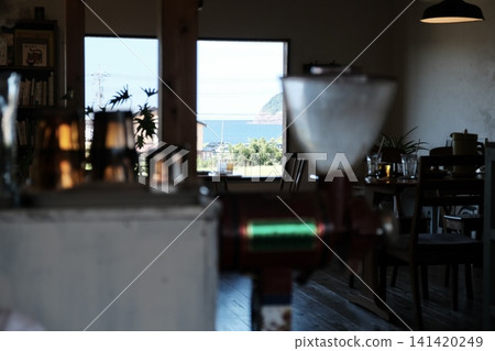 安靜的咖啡館，窗外可以俯瞰大海，前景中擺放著一台復古的咖啡研磨機。 141420249