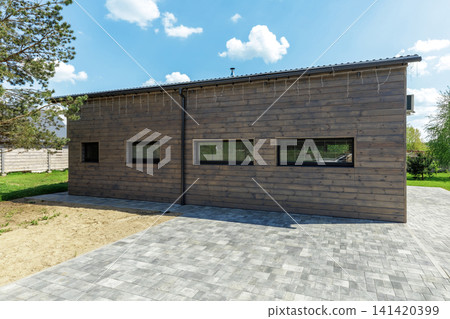 Modern Wooden House Facade with Paved Driveway 141420399