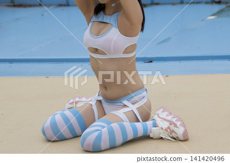 一個穿著泳衣的女人坐在泳池邊 一個穿著泳衣的女人坐在泳池邊 141420496