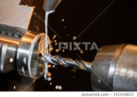 High-precision lathe machine performing a hole making process on a ring shape part with liquid coolant. High-precision lathe machine performing a hole making process on a ring shape part with liquid coolant. 141420655