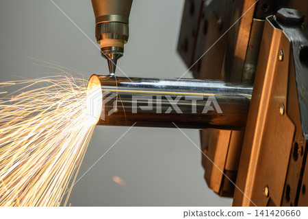 Operation of a high-power fiber laser cut machine cutting a stainless steel tube with sparkling light. 141420660
