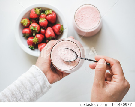 Hands stirring strawberry yogurt with a spoon Hands stirring strawberry yogurt with a spoon 141420977