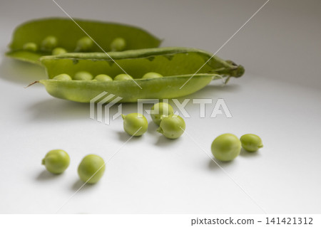 Fresh green peas in an open pod isolated on a white background. Close up shot of organic legumes, healthy food ingredient, raw vegetable, natural harvest, vegan nutrition, vegetarian eating concept. Fresh green peas in an open pod isolated on a white background. Close up shot of organic legumes, healthy food ingredient, raw vegetable, natural harvest, vegan nutrition, vegetarian eating concept. 141421312