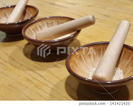 Three Wooden Mortars with Pestles and Sesame Seeds Closeup Three Wooden Mortars with Pestles and Sesame Seeds Closeup 141421420