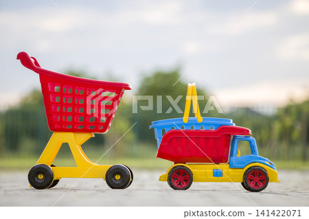 Bright plastic colorful toys for children outdoors on sunny summer day. Car truck, basket and shopping pushcart. Bright plastic colorful toys for children outdoors on sunny summer day. Car truck, basket and shopping pushcart. 141422071