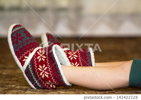 Bare child legs and feet in red winter christmas boots with ornament pattern Bare child legs and feet in red winter christmas boots with ornament pattern 141422128