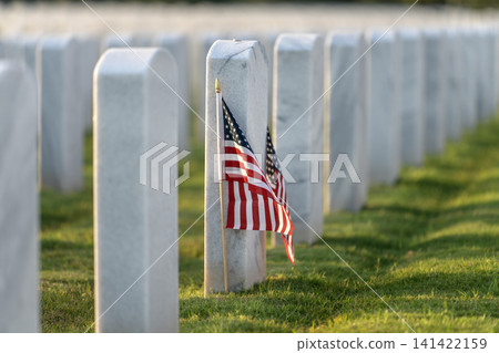 American national military cemetery with rows of white tomb stones and USA flag on green grass lawn. Memorial Day concept 141422159