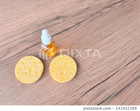 Vitamin C serum and two sponges on a wooden table, top view Vitamin C serum and two sponges on a wooden table, top view 141422389