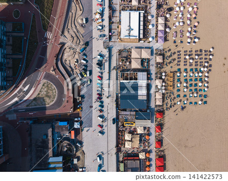Beautiful top down high altitude aerial panoramic perspective of beach resort clubs with sunbeds umbrellas and colorful vintage cars parked near a boulevard roundabout under bright sunlight Beautiful top down high altitude aerial panoramic perspective of beach resort clubs with sunbeds umbrellas and colorful vintage cars parked near a boulevard roundabout under bright sunlight 141422573