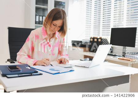 Pretty businesswoman working with laptop at table in office Pretty businesswoman working with laptop at table in office 141422906