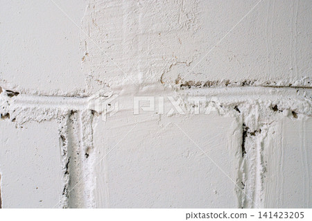 White painted block wall texture. White concrete bricks with messy mortar layers, uneven surface, and cracks White painted block wall texture. White concrete bricks with messy mortar layers, uneven surface, and cracks 141423205
