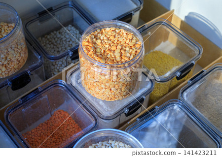 Food storage system. Clear plastic containers filled with flour and grains. Storing dry goods in airtight containers in a kitchen cabinet drawer. Food storage system. Clear plastic containers filled with flour and grains. Storing dry goods in airtight containers in a kitchen cabinet drawer. 141423211