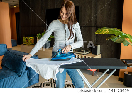 Woman in jeans doing housework and ironing clothes Woman in jeans doing housework and ironing clothes 141423609