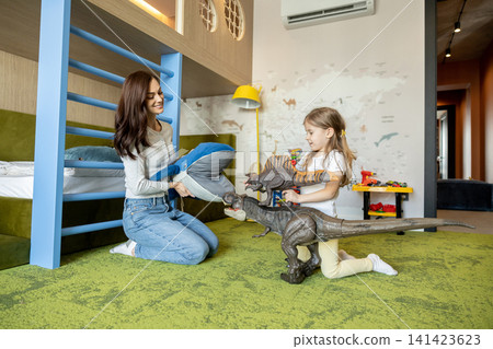 Mom and daughter playing together with dinosaurs and looking happy Mom and daughter playing together with dinosaurs and looking happy 141423623