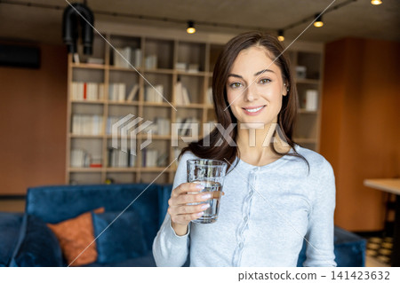 Pretty young woman with a glass in hands smiling nicely Pretty young woman with a glass in hands smiling nicely 141423632