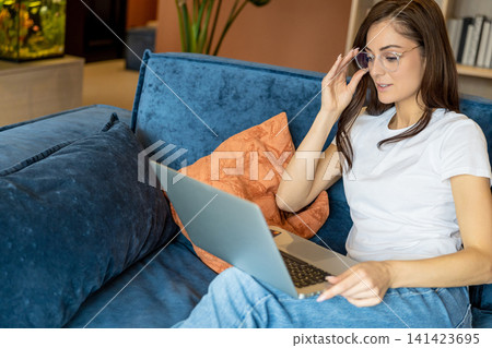 Young woman in eyeglasses working on a laptop and looking busy 141423695