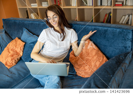 Young woman in eyeglasses working on a laptop and looking busy 141423696
