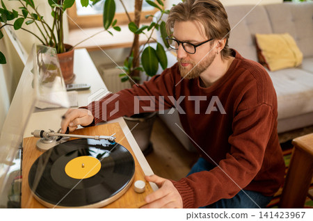 Young bearded caucasian man playing a stereo record Young bearded caucasian man playing a stereo record 141423967