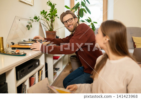 Man and woman spending time at home and choosing a music record Man and woman spending time at home and choosing a music record 141423968