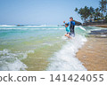 Caucasian father and son joyfully splashing in tropical waves on Sri Lankan beach 141424055
