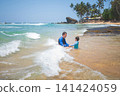 Caucasian father and son playing in shallow tropical waters on Sri Lankan beach 141424059
