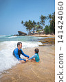 Caucasian father and son playing in shallow water on a tropical Sri Lankan beach 141424060