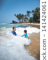 Caucasian father and son playing in ocean waves on tropical Sri Lankan beach 141424061