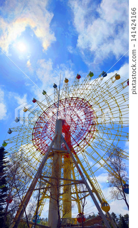 An amusement park with a Ferris wheel floating in the blue sky. An amusement park with a Ferris wheel floating in the blue sky. 141424166