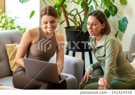 Fitness coach and student using laptop Fitness coach and student using laptop 141424359