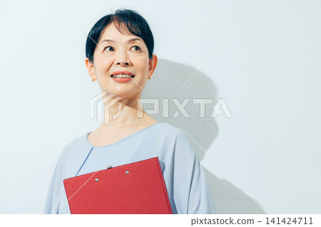 A senior woman smiling while holding a file A senior woman smiling while holding a file 141424711