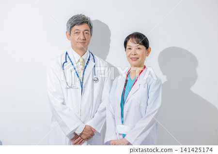一男一女兩位醫生面帶微笑地站著。 一男一女兩位醫生面帶微笑地站著。 141425174