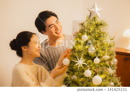 一對夫婦正在裝飾聖誕樹 一對夫婦正在裝飾聖誕樹 141425231