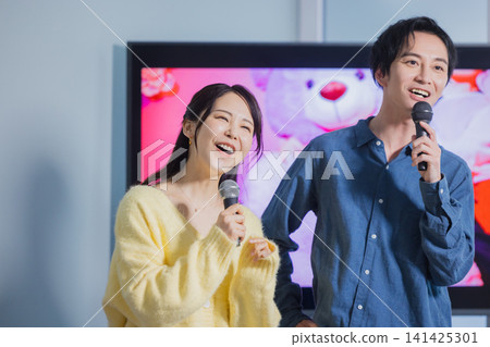 A man and a woman singing karaoke A man and a woman singing karaoke 141425301