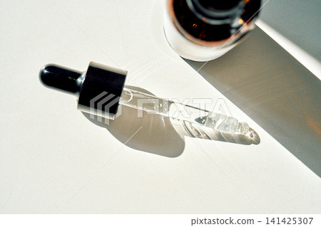 Pipette applying serum on white background with bottle Pipette applying serum on white background with bottle 141425307