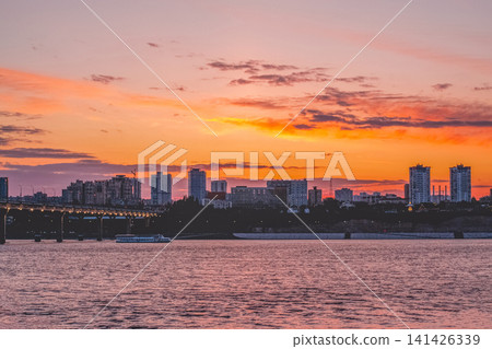 Volgograd, Russia - 05.25.2023: Volgograd city skyline at sunset over the Volga River in Russia. Beautiful urban landscape with bridge, residential buildings and colorful orange and pink sky. Evening Volgograd, Russia - 05.25.2023: Volgograd city skyline at sunset over the Volga River in Russia. Beautiful urban landscape with bridge, residential buildings and colorful orange and pink sky. Evening 141426339