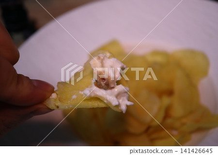 Hand Holding Potato Chip with Creamy Dip Hand Holding Potato Chip with Creamy Dip 141426645