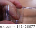 Hand Holding Measuring Cup with Volume Markings 141426677