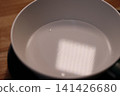 Water in White Bowl on Wooden Surface 141426680