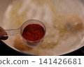 Measuring Spoon with Red Spice Over Pan 141426681
