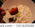 Measuring Cup with Paprika Over Soup Bowl 141426686