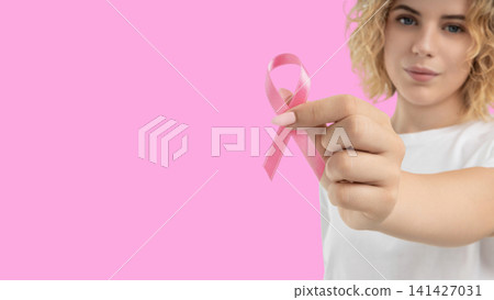 A woman holds a pink ribbon to promote cancer awareness A woman holds a pink ribbon to promote cancer awareness 141427031