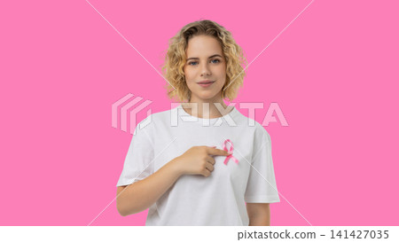 Woman points to pink ribbon symbolizing cancer awareness Woman points to pink ribbon symbolizing cancer awareness 141427035