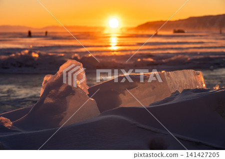 Cracked ice on frozen lake Baikal at sunset seen from Listvyanka town, Russia. Cracked ice on frozen lake Baikal at sunset seen from Listvyanka town, Russia. 141427205