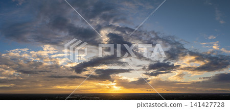 Colorful sunset sky with setting sun behind vivid orange and yellow clouds Colorful sunset sky with setting sun behind vivid orange and yellow clouds 141427728