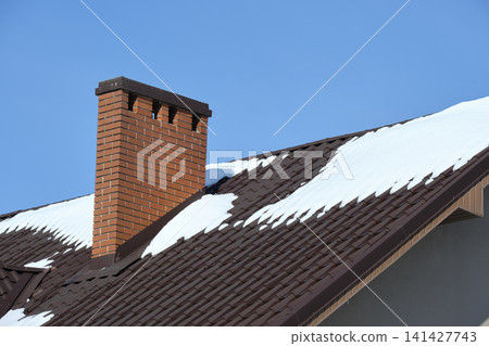 Closeup of house roof top covered with snow in cold winter. Tiled covering of building in wintertime weather 141427743